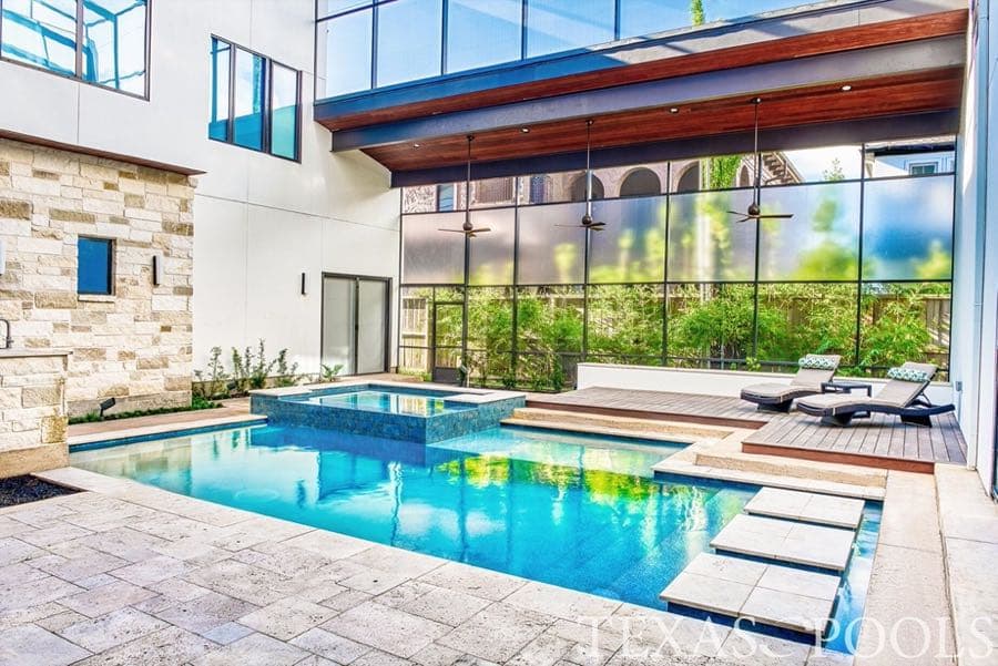 Modern courtyard pool and spa with glass-wall backdrop